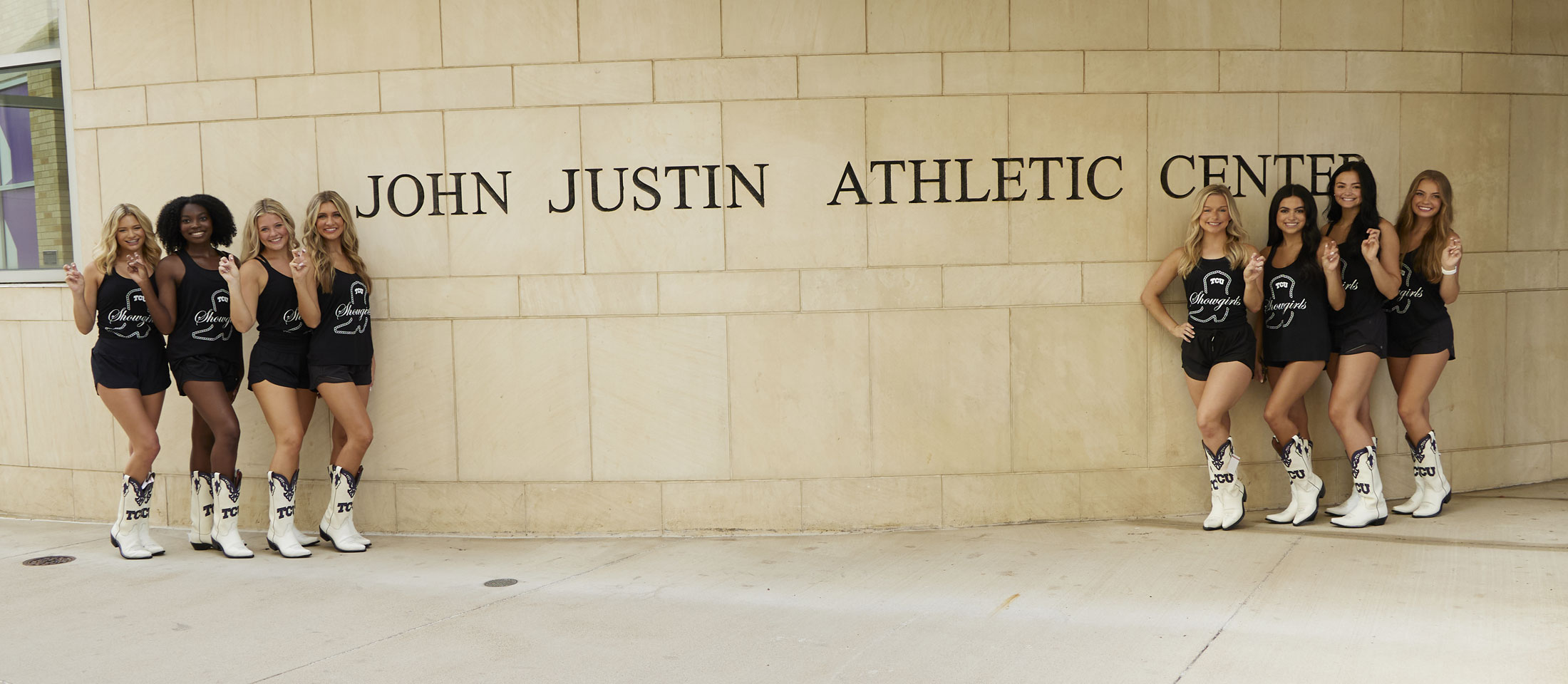 TCU Showgirls pose next to the John Justin Athletic Center in their custom Justin Boots.